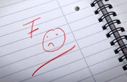 F grade and sad smilie written in a spiral pad